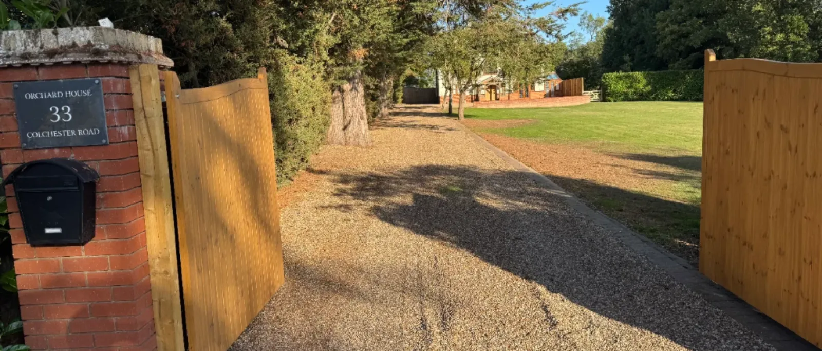 The gated gravel driveway to Orchard House, 33 Colchester Road, Great Totham, with the Elaris clinic building beyond