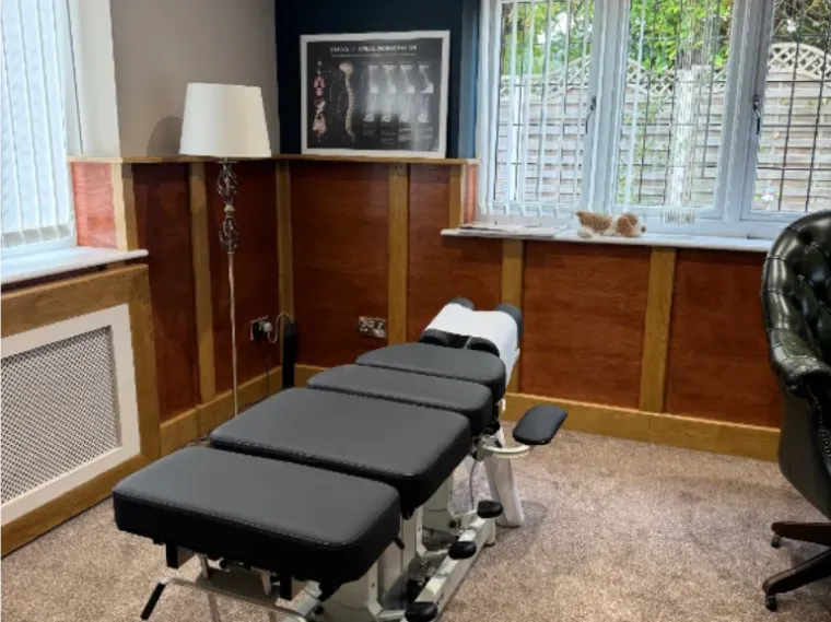 Treatment room at Elaris Chiropractic with an adjusting bench and a spinal x-ray chart on the wall